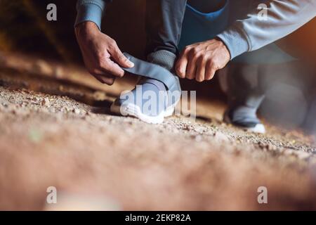 Nahaufnahme Ansicht Hände und Schuhe von sportlich aktiv afro amerikanischen Läufer Mann hocken und binden Klettverschluss Turnschuhe in der verlassenen sonnigen Ort. Stockfoto
