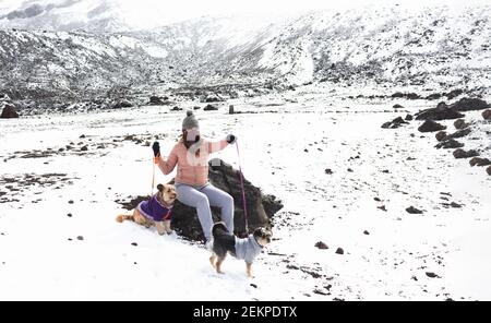 Teen Mädchen mit Maske sitzt mit ihren Hunden auf einem Schneebedeckter Berg Stockfoto