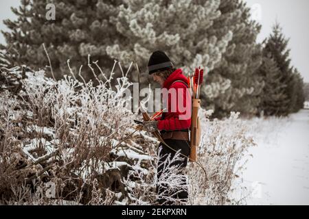 Teen junge Blick auf Tierfalle im Winter Wisconsin mit Pfeil und Bogen Stockfoto