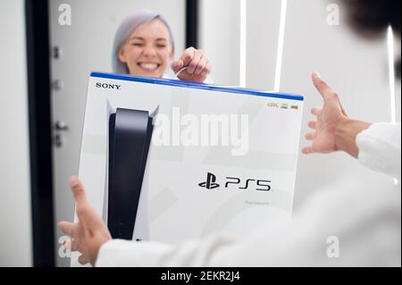 Frau überrascht ihren Bruder mit einer Sony playstation 5-Konsole der nächsten Generation, Online-Shopping-Geschenk, moderne Videospiel-Gerät für Cyber-Sport. Moskau - Stockfoto