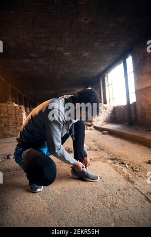 Nahaufnahme des sportlich aktiven afro amerikanischen Runner man hocken und binden Klett Sneakers in der verlassenen sonnigen Ort. Stockfoto