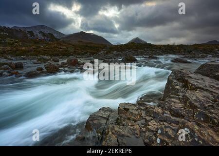 Lange Exposition von Wasser mit Felsen im Vordergrund, Wintervegetation auf dem Fluss Sligachan auf der Isle of Skye Schottland mit dem Cuillin Berg r Stockfoto