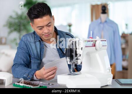 Mechanische Reparatur Nähmaschine liest Anweisungen Stockfoto