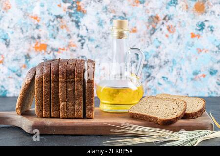 Braune Brotscheiben und Ölflasche auf Holzbrett Stockfoto