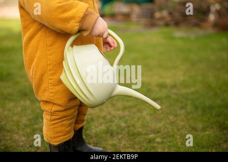 Ein kleines Kind hilft im Garten Pflanzen wässern Mit einer Gießkanne Stockfoto