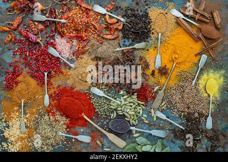 Aromatische Gewürze auf Löffeln auf Schieferhintergrund Stockfoto