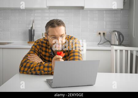 Mann mittleren Alters mit Brille während eines Online-Termins. Videogespräch mit einer Freundin. Das Konzept einer Beziehung während der Quarantäne. Stockfoto