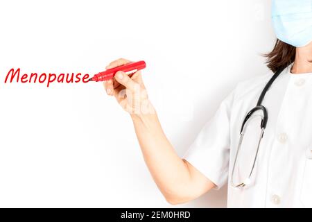 Arzt mit Maske, die das Wort Wechseljahre mit einem roten Marker auf weißem Hintergrund schreibt. Gesundheitskonzept Stockfoto