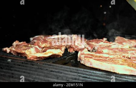 Fleischgerichte auf einem gasbetriebenen Grill in einem Haus in Sydney, Australien, mit Rauch, der aus dem Feuer darunter steigt Stockfoto