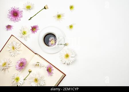 Lesen eines Buches im Frühjahr. Ein Buch mit frischen Frühlingsblumen und einer Tasse Kaffee. Gemütlicher Morgen mit erfrischendem schwarzen Kaffee und einem interessanten Buch Stockfoto