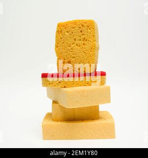 Ein lebhafter Stapel von Küchenschwämmen in gelben und roten Farben vor einem minimalistischen Hintergrund Stockfoto