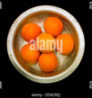 Frische Orangen in einer Edelstahlschale auf dunkler Oberfläche, die ihre leuchtende Farbe und ihren gesunden Anblick zum Ausdruck bringt Stockfoto