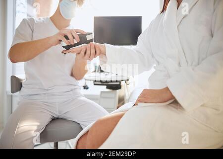Spa-Klientin, die ihren Gesundheitszustand von einem bebretteten überprüft hat Arzt Stockfoto