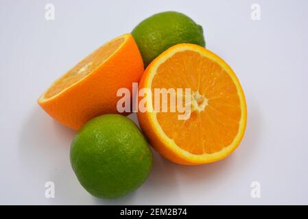 Gesunde reife köstliche Früchte für die menschliche Gesundheit. Saftige Früchte von Orange, Limette. Zwei Hälften einer Orange, zwei ganze Limetten. Stockfoto