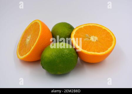 Gesunde reife köstliche Früchte für die menschliche Gesundheit. Saftige Früchte von Orange, Limette. Zwei Hälften einer Orange, zwei ganze Limetten. Stockfoto