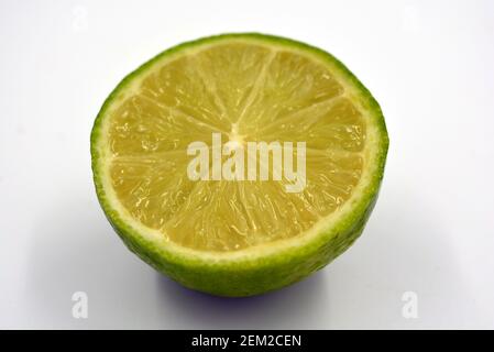 Gesunde reife köstliche Früchte für die menschliche Gesundheit. Saftige Früchte von grünsaurem Kalk. Eine Hälfte einer in Scheiben geschnittenen Limette auf weißem Hintergrund. Stockfoto