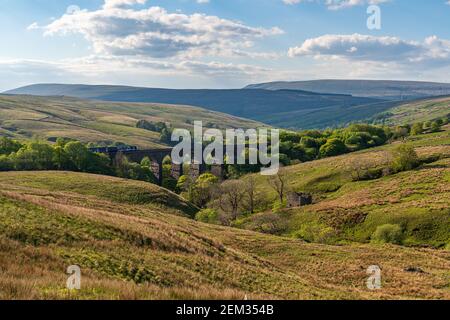 In der Nähe von Cowgill, Cumbria, England, Großbritannien - 16. Mai 2019: Ein Zug, der am Dent Head Viaduct vorbeiführt, mit der Dent-Dale-Landschaft im Hintergrund Stockfoto