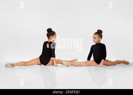 Zwei junge schöne Turnerin Mädchen in schwarzer Sportbekleidung führt Gymnastik Posen Stockfoto