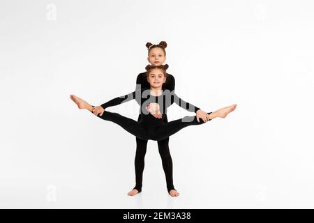 Zwei Turnerin Kindermädchen zeigen sportliche Fähigkeiten auf weißem Studio Hintergrund. Kinder zeigt Querfaden Stockfoto