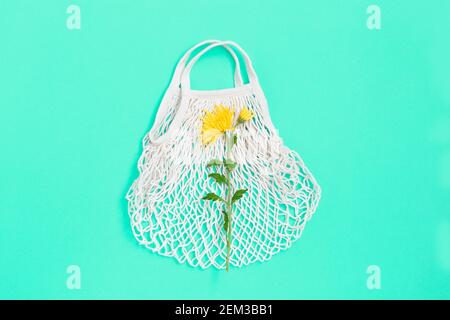 Weiße Öko-Tasche Mesh-Textur mit Blume auf blauem Hintergrund. Flach liegend Stockfoto