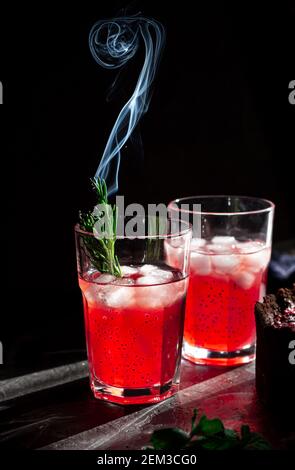 Erstaunliche Komposition mit Erdbeer-Käsekuchen und Erdbeergetränk mit Rosmarin. Nur ein Teil des Käsekuchen im Fokus und ein Teilchen eines Glases d Stockfoto