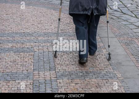 Ältere Dame zu Fuß mit Wanderstöcken auf der Straße in Prag, Tschechische Republik. Stockfoto
