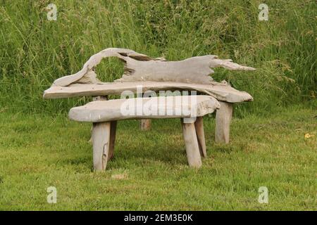 Eine rustikale Holzbank im Freien und ein kleiner Tisch. Stockfoto