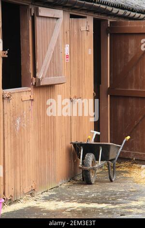 Ein ausmuckender Schubkarre an einem Pferdestall. Stockfoto