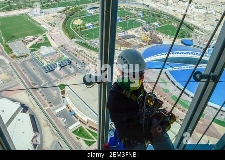 KATAR, Doha, Aspire Dome und Sportpark im Khalifa International Stadium für die FIFA WM 2022 arbeiten philippinische Wanderarbeiter als Fensterputzer im Aspire Tower / KATAR, Doha, Fussballfelder und Sportpark am Khalifa International Stadium für die FIFA Fussballweltmeisterschaft 2022, philipinische Gastarbeiter arbeiten als Fensterreiniger am Aspire Tower Stockfoto