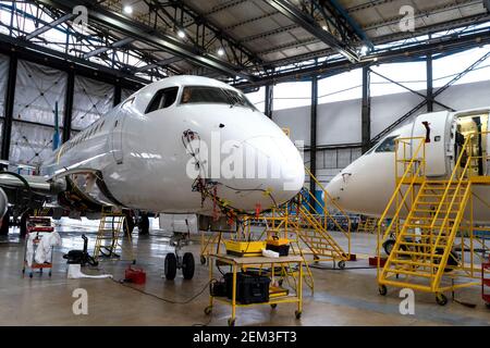 Flugzeuge befinden sich im Hangar für technische Reparatur und Wartung. Flugzeugdiagnose, Lagerung, Service. Ebene. Leitern für Mechaniker. Stockfoto