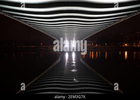 Abstrakte Flussspiegelung unter der Brücke mit Lichtern. Futuristische Brücke über dem Fluss. Abnehmende Perspektive Stockfoto