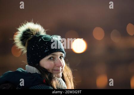 Weiße Frau mit Strickmütze und Brille auf Hut, suchen und Smignieren an die Kamera. Fröhliche und fröhliche Winterstimmung. Stockfoto