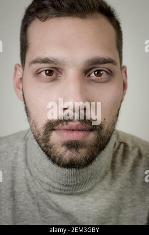 Porträt eines jungen braunhaarigen Mannes mit kurzem Bart Und einen grauen Rollkragenpullover Stockfoto