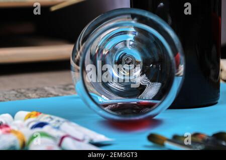 Bunte Ölgemälde Tuben, Pinsel und ein Glas Wein auf dunklem Tisch Stockfoto