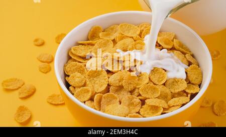 Milch gießt in Schale mit Maisflocken Stockfoto