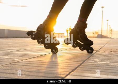 Nahaufnahme der Frauenbeine mit Rollschuhe bei Sonnenuntergang Kreatives Sport- und Rollschuh-Lifestyle-Konzept an sonnigen Tagen. Stockfoto