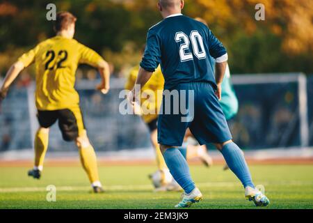 Erwachsene Männer Spielen Europäischen Fußball. Fußballspieler laufen und treten Spiel. Erwachsene Fußballspieler treten im Fußballspiel an. Fußball Bank und Sub Stockfoto