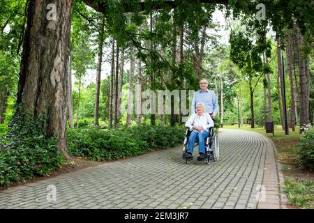 Seniorenpaar zusammen durch harte Zeiten verbringen Zeit zusammen im Park, Rollstuhl-Konzept Stockfoto