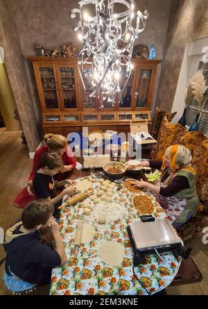 Großmutter beim Backen von Lahmacun mit Enkeln im Speisesaal, Mehrgenerationenbacken einer türkischen Familie, Deutschland Stockfoto