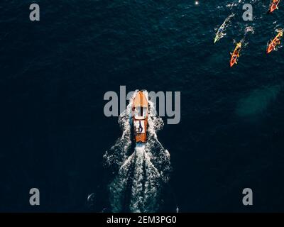 Luxuriöses Holzmotorboot rauscht durch die Wellen der Adria. Touristen segeln auf Kajaks mit Rudern. Stockfoto