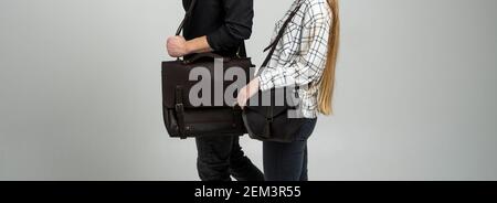 Braune Männer Schulter Ledertasche für ein Dokument und Laptop hält von Mann in einem schwarzen Hemd und Frau mit einer schwarzen kleinen Tasche. Stil, Retro, Mode Stockfoto