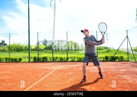 Junger Mann, der auf dem Sandplatz trainiert und Tennis spielt Stockfoto
