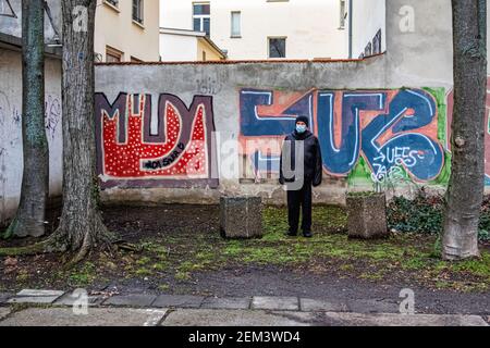 Innenhofgarten des Mehrfamilienhauses in der Linienstraße, Mitte-Berlin, Deutschland. Älterer Mann mit Gesichtsmaske während der Covid-Pandemie Stockfoto