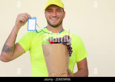 Kaukasischen Delivery Mann Arbeiter in gelber Farbe einheitliche Handhabung Beutel mit Lebensmitteln, Obst und Gemüse. Food and Delivery Konzept. Stockfoto