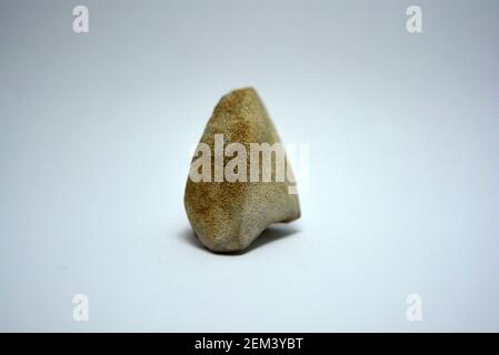 Ein Stein, ein behauener Stein, ein Splitter aus einem weißen Zementstein, der aus dem Meerwasser genommen und auf einen weißen Hintergrund gestellt wurde. Stockfoto