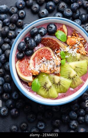 Detox lila acai Smoothie Schüssel mit Heidelbeeren, Kiwi, Feigen, Müsli und Kokosnussdecken Stockfoto