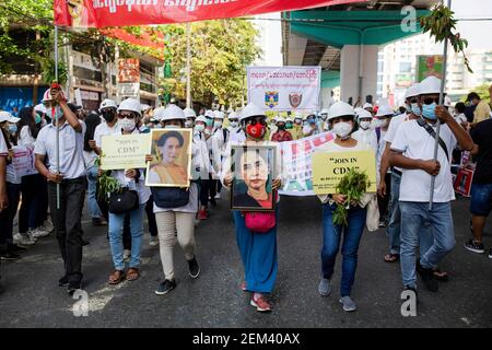 Zwei Demonstranten führten den marsch mit Porträts von Aung San Suu Kyi an, während zwei andere während der Demonstration ein großes Banner hochhielten.EINE riesige Menschenmenge ging auf die Straßen von Yangon, um gegen den Militärputsch zu protestieren und forderte die Freilassung von Aung San Suu Kyi. Das Militär von Myanmar nahm am 01. Februar 2021 die staatliche Beraterin von Myanmar Aung San Suu Kyi fest und erklärte den Ausnahmezustand, während sie die Macht im Land für ein Jahr ergattete, nachdem sie die Wahl gegen die National League for Democracy (NLD) verloren hatte. Stockfoto