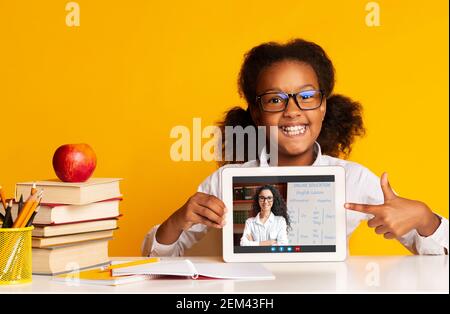 Schwarzes Mädchen zeigt Pad Bildschirm, mit Video-Chat mit Lehrer Stockfoto