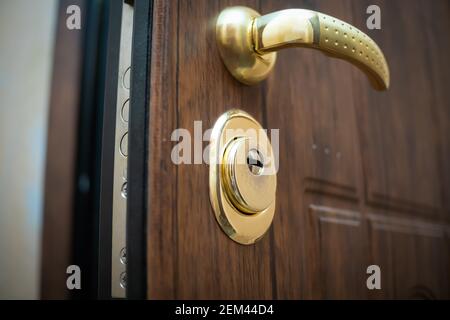 Nahaufnahme des goldenen Griffs, das Schloss der offenen schönen braunen Haustür Stockfoto