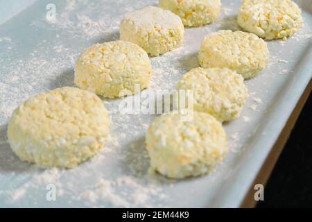 Viele Hüttenkäse Pfannkuchen auf einem weißen Tablett mit Mehl schließen vor dem Braten in einer Pfanne. Selektiver Fokus Stockfoto